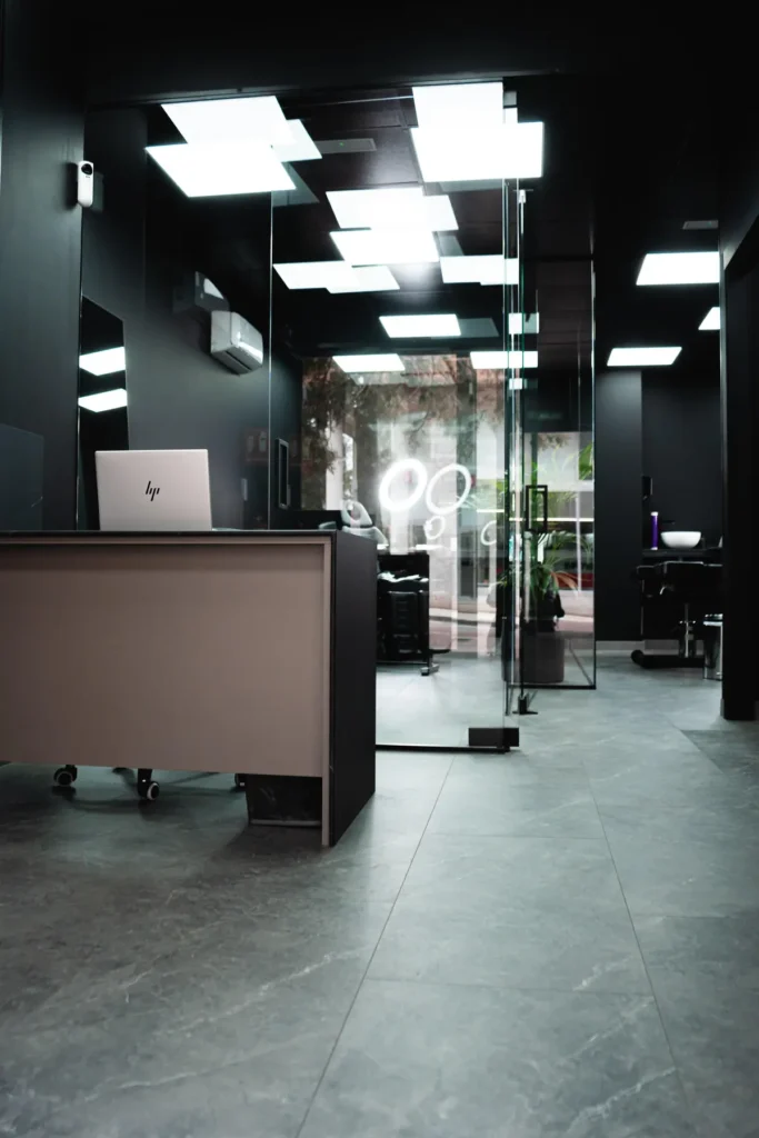 Recepción vista en profundidad: mostrador, mamparas de vidrio y paneles de luz en el techo negro