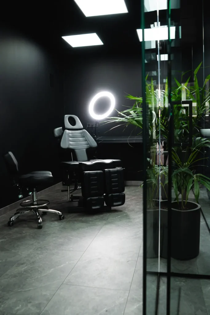 Sala de trabajo con suelo gris, paredes negras, mampara de vidrio y plantas
