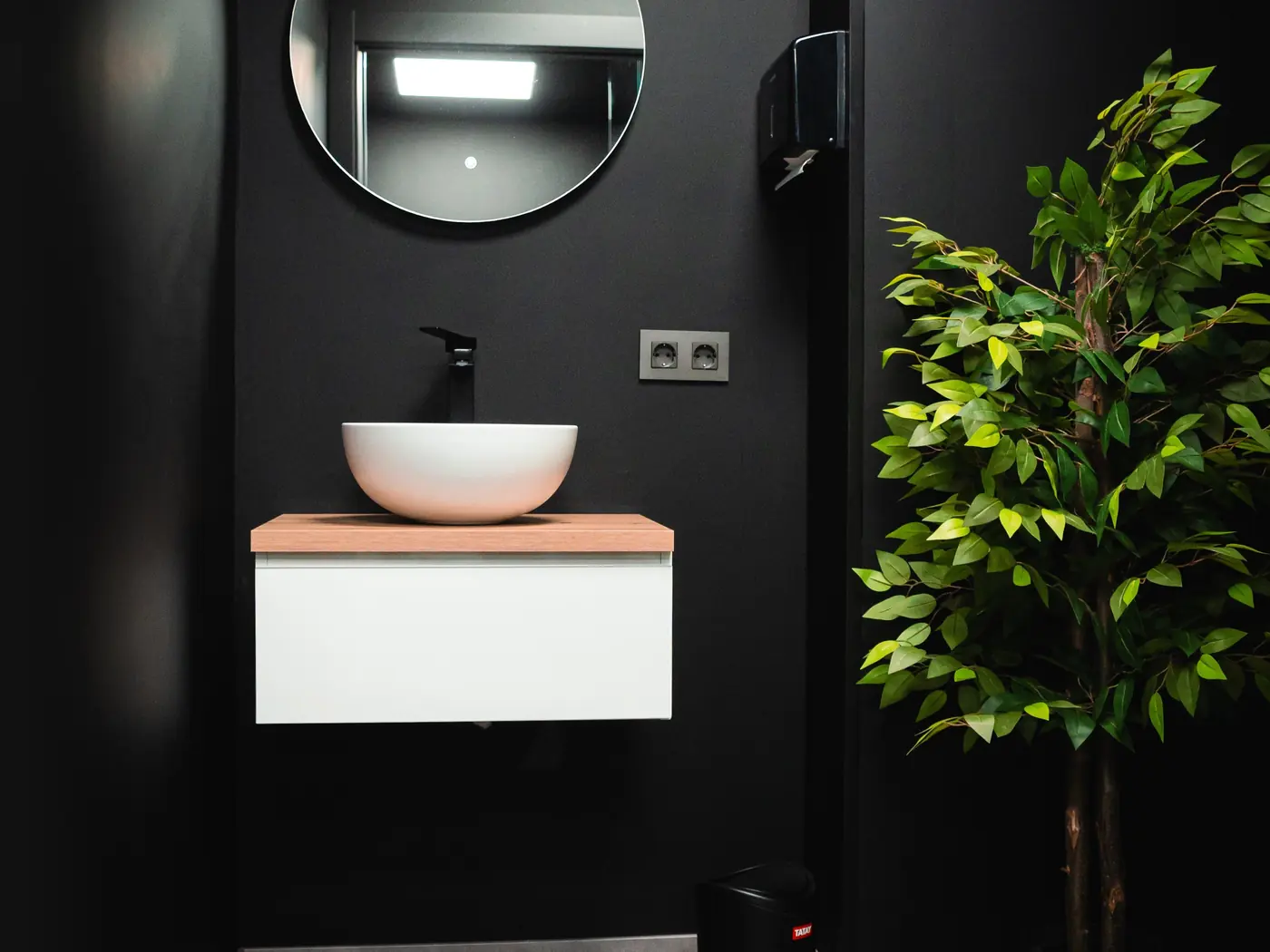 Aseo del local reformado: espejo redondo, lavabo sobre mueble volado y planta