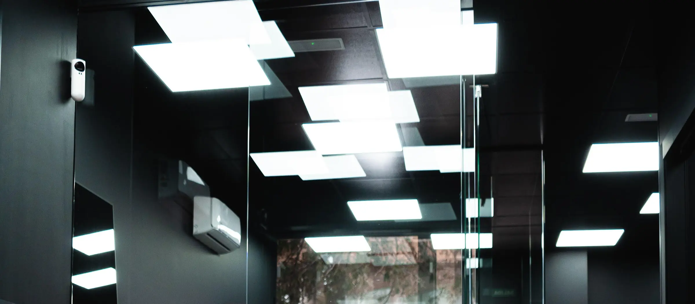 Techo negro del local con la composición de paneles de luz y las mamparas de vidrio